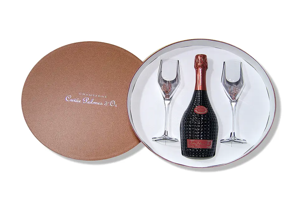 Cuvée Palmes d'Or - Boîte ronde couvercle coiffant carton 8 et 15/10 1 face blanche contrecollé rembordé d’un papier de création – Impression à chaud argent – grille de calage en carton recouvert d’un papier couché et de paillettes projetées à la bombe.